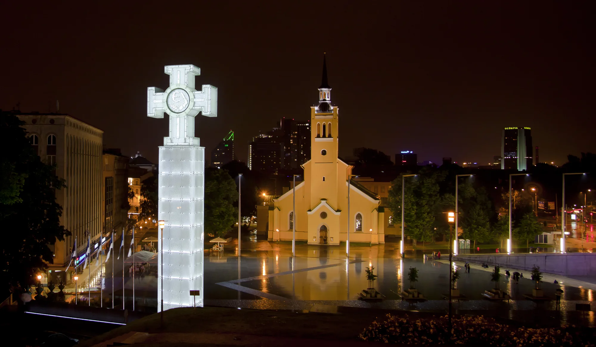 Freedom Square (Vabaduse väljak) in Tallinn at night with the illuminated glass Victory Column (War of Independence monument) and St John's Church