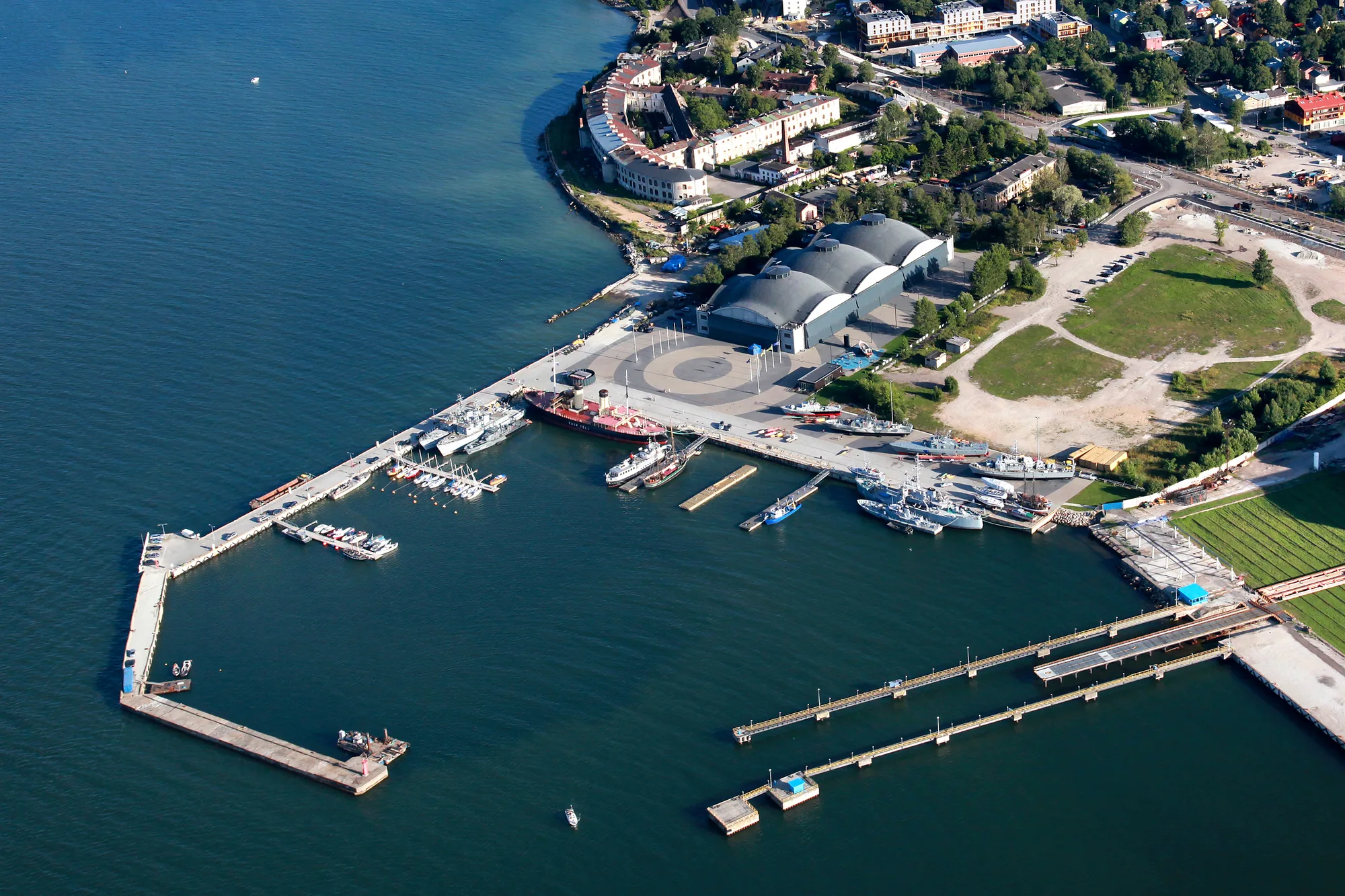 Aerial view of the Seaplane Harbour (Lennusadam) Maritime Museum in Tallinn, with its three domed concrete hangars and historic ships in the harbour basin